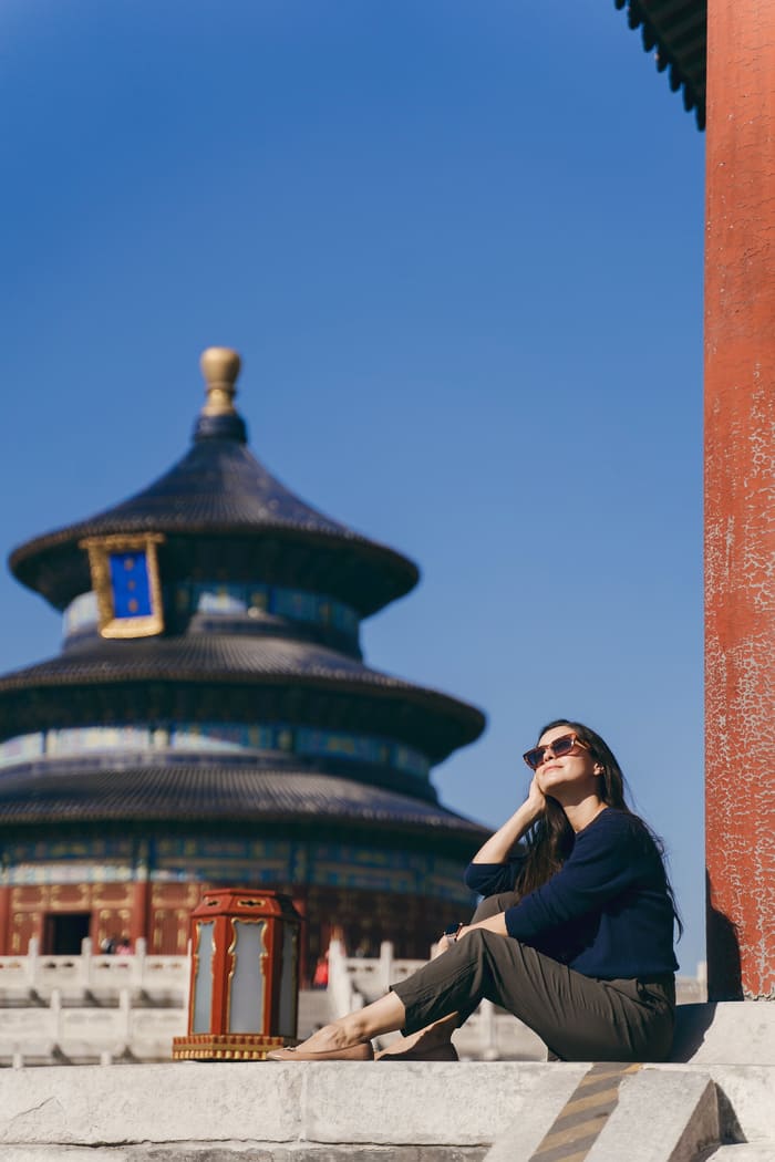 Mujer turista posando en una fotografia con templo chino de fondo.